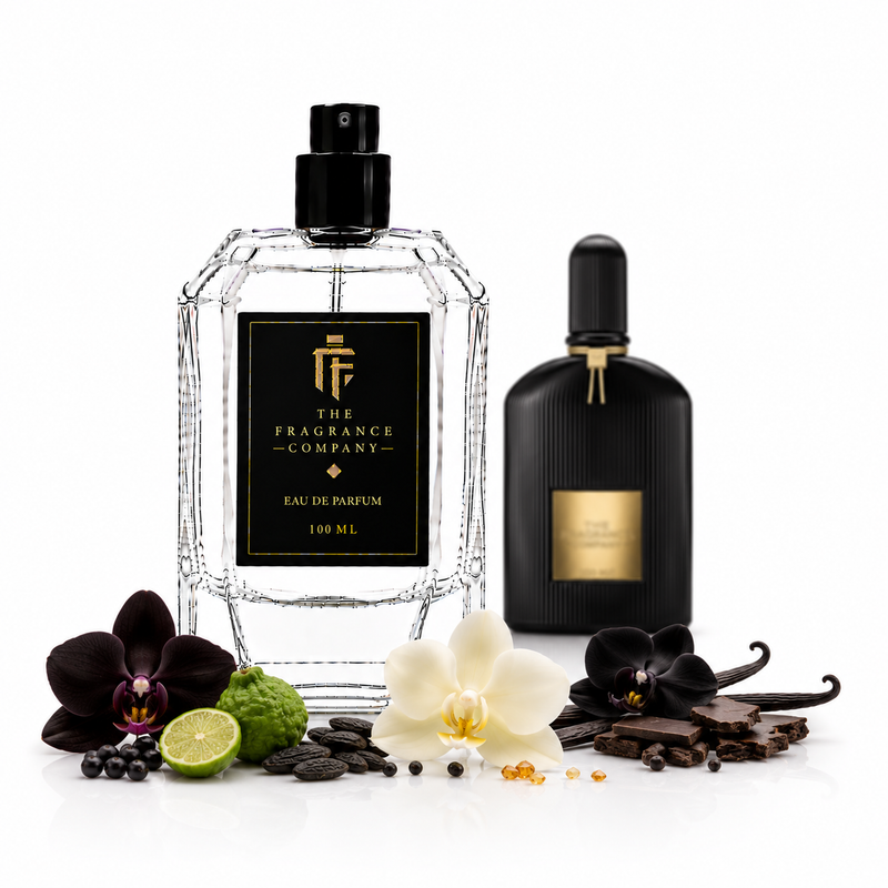 Two perfume bottles from The Fragrance Company are displayed on a white background with botanical and food props. The main bottle is a faceted clear glass bottle with a black cap and a black label featuring a gold logo and text.