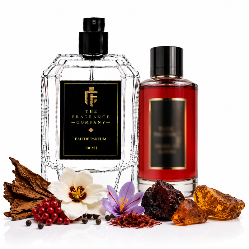Two fragrance bottles from The Fragrance Company on a white background, surrounded by botanical and aromatic ingredients. The left bottle is a clear glass Eau de Parfum with a black cap and black label, and the right bottle is a red glass bottle with a black cap and black label.
