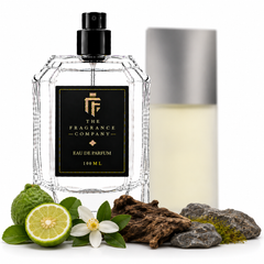 A clear glass perfume bottle with a black spray top and a black front label reading 'THE FRAGRANCE COMPANY' and 'EAU DE PARFUM 100 ML', styled with citrus, wood, moss, and rocks on a white background. A second bottle with a silver cap stands blurred in the background.