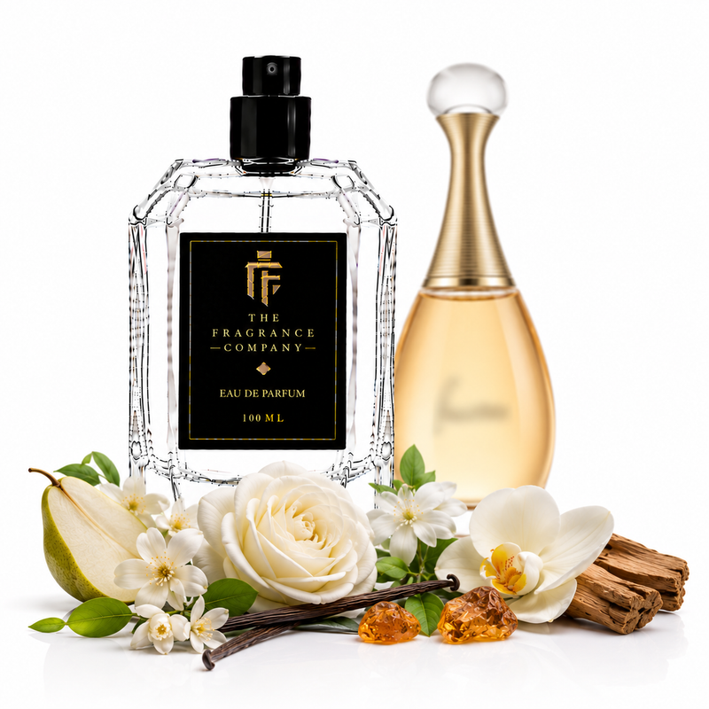 Two perfume bottles from The Fragrance Company on a white background, styled with white roses, a pear, vanilla beans, amber crystals, and cinnamon sticks. The front bottle is a clear faceted glass spray bottle with a black label and black sprayer, and the rear bottle is a gold-toned glass perfume bottle with a white spherical cap.
