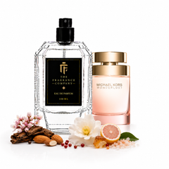 Two perfume bottles on a white background: a large clear glass bottle with a black pump and black label reading The Fragrance Company Eau de Parfum 100 ML, and a Michael Kors Wonderlust bottle with a gold cap and pale pink body. Decorative flowers, nuts, spices, and citrus pieces are arranged around the bottles.