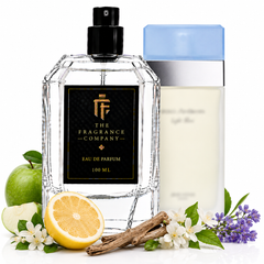 A perfume bottle labeled 'THE FRAGRANCE COMPANY' with a black label and black spray top, shown alongside a cream-colored bath/body container with a light blue cap. The scene is styled with a green apple, sliced lemon, cinnamon sticks, white flowers, and purple blossoms on a white background.