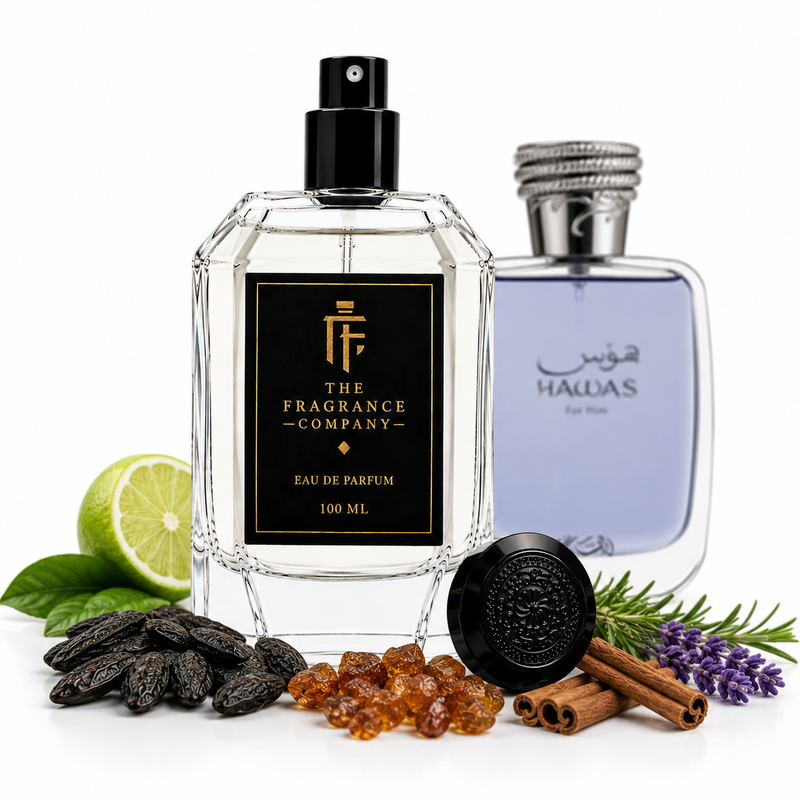 Two perfume bottles displayed on a white background with scent ingredients around them. The front bottle is a faceted clear glass spray bottle labeled 'THE FRAGRANCE COMPANY' with a black label and black spray top.